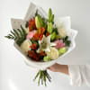 Hand-tied bouquet of white roses, lilies, and orange flowers in white paper