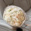 Bouquet of white orchids, cream roses, and hydrangeas wrapped in clear paper