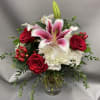 Red roses and white lilies in a glass vase with white hydrangea