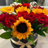 Red roses and yellow sunflowers arranged in a round black box with a ribbon