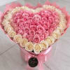 Heart-shaped bouquet of pink and cream roses in a pink box