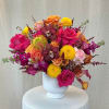 Bright mixed bouquet in a white vase with roses, orchids, and mums