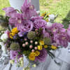 Bouquet of pink orchids, lavender roses, and yellow spray roses in a vase