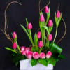 Pink tulips and roses arranged in a white rectangular container