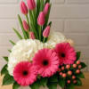 Fresh pink tulips, vibrant pink gerbera daisies, white hydrangeas, and hypericum berries