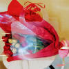 Red rose bouquet wrapped in red and clear plastic with a pink ribbon