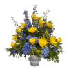 Yellow roses and blue flowers arranged in a gray vase