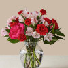 Pink rose and red carnation bouquet in a clear glass vase