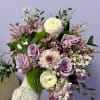 Handheld bouquet of lavender roses, white ranunculus, and pink blooms