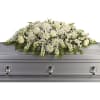 White floral casket spray on a gray casket