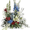Floral funeral urn arrangement with lilies, roses, and tall blue and white spikes