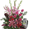 Pink lilies and roses arranged beside a silver urn