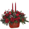 Red rose arrangement with two tall red candles in a red container