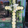 White floral cross arrangement on an easel with lilies and chrysanthemums