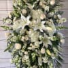 Large white funeral spray with lilies, roses, and cascading blooms