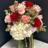Bouquet of pink and red roses with white hydrangea in a glass vase