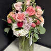 Pink and white bouquet in a clear glass vase with a striped ribbon