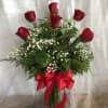 Red roses in a glass vase with baby's breath and a red ribbon