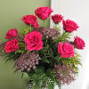 Pink roses arranged in a clear glass vase with purple filler flowers