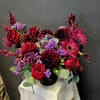 Red roses and magenta flowers arranged in a black vase