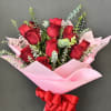 Bouquet of red roses wrapped in pink paper with a red ribbon