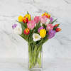 Mixed tulips in pink, yellow, white, red, and purple in a clear glass vase