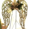 Floral arrangement on decorative angel wings with pale flowers and dark green leaves