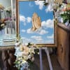 Floral funeral easel with white flowers and a framed praying hands tribute