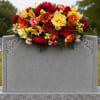 Bright mixed flower arrangement placed on a gray gravestone
