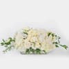 Low rectangular centerpiece of ivory roses and white blooms in a clear glass vase