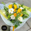 Hand-tied bouquet of yellow roses and white gerbera daisies wrapped in white and yellow mesh.