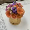 Bouquet of orange gerberas, pink roses, and purple flowers in a gold box