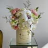 Pink roses and white orchids arranged in a cream hat box