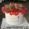 Round box of red tulips with green leaves
