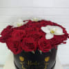 Red roses and white orchids arranged in a black round box