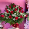 Red roses arranged in a clear vase with white baby's breath