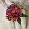 Bride holding a bouquet of purple and coral flowers