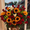 Bouquet of red roses, sunflowers, white lilies, and red carnations in a painted vase