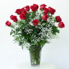 Red roses arranged in a clear glass vase with white baby's breath