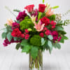 Bouquet of red roses, pink lilies, and purple flowers in a glass vase