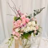 Pink and white rose arrangement in a clear glass vase with ribbon
