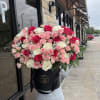 Large bouquet of pink and white roses in a black hatbox