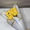 Bouquet of yellow roses wrapped in white paper with gold trim