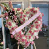 Heart-shaped pink and white floral standing spray with a ribbon across it