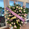 Large standing floral spray with a pink memorial ribbon