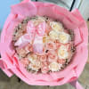 Pink-wrapped bouquet of pale pink and white roses with a satin bow