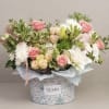 Pink and white flower arrangement in a patterned box