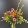 Mixed bouquet of orange and pink flowers in a clear glass vase