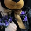 Black teddy bear with purple floral accents and a gold ribbon bow