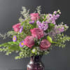 Pink roses and purple flowers in a dark glass vase